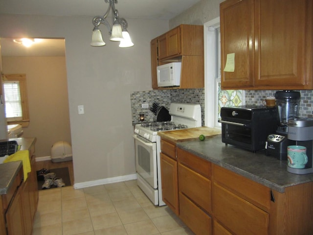 kitchen featuring white appliances, decorative light fixtures, decorative backsplash, and light tile patterned flooring