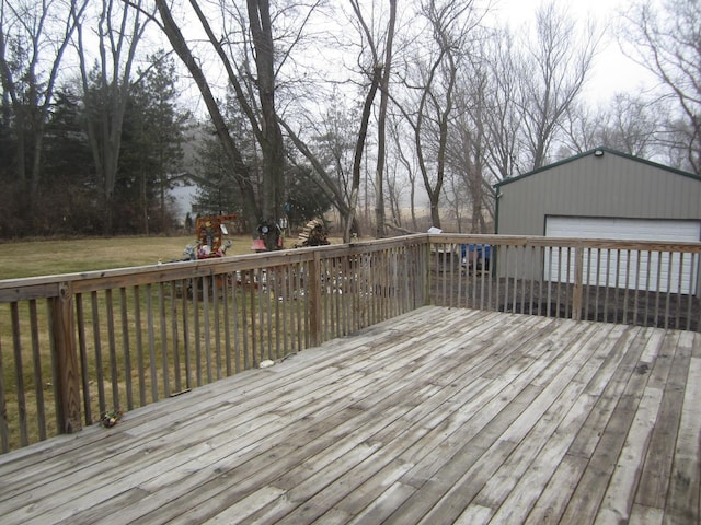 wooden deck featuring a garage, a yard, and an outbuilding