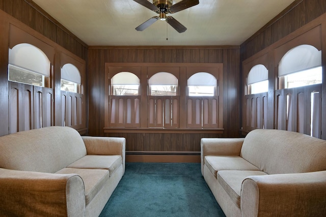 living area with a baseboard radiator, ceiling fan, and wood walls