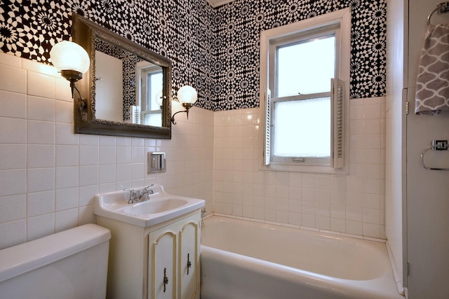 bathroom with plenty of natural light, a bathing tub, tile walls, and vanity