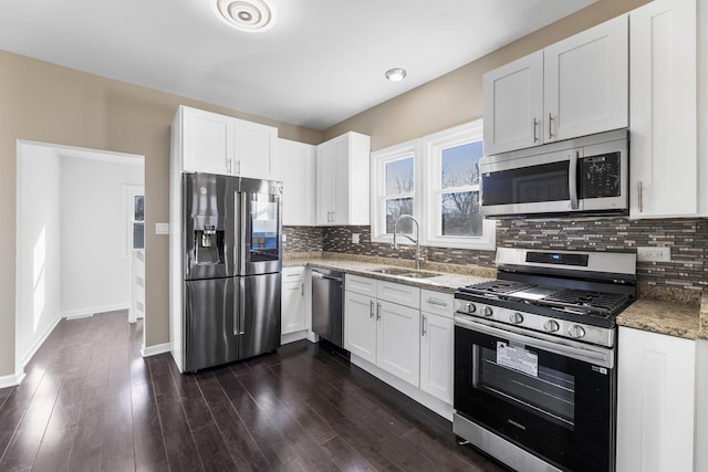 kitchen with sink, stainless steel appliances, white cabinets, stone countertops, and decorative backsplash