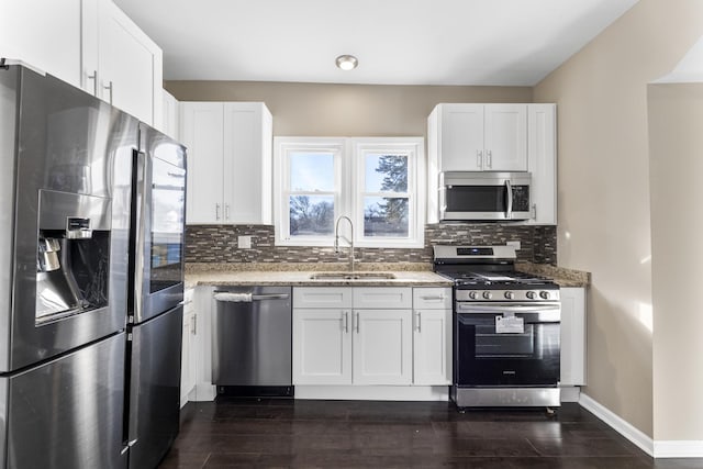 kitchen featuring stainless steel appliances, sink, white cabinets, and light stone counters