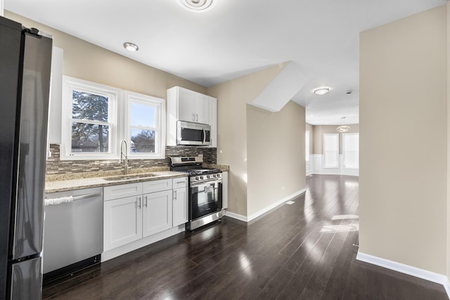 kitchen featuring sink, white cabinetry, backsplash, stainless steel appliances, and light stone counters