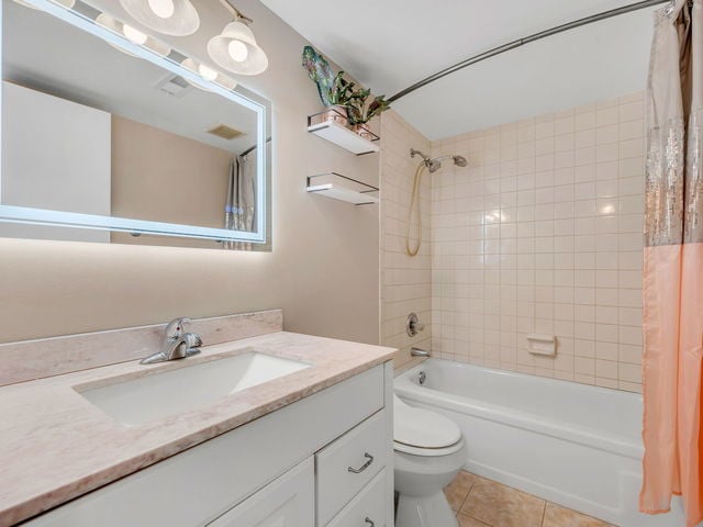 full bathroom with tile patterned flooring, vanity, shower / bath combo, and toilet