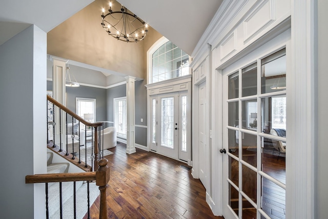 foyer entrance with dark wood-style flooring, french doors, stairway, a chandelier, and ornate columns