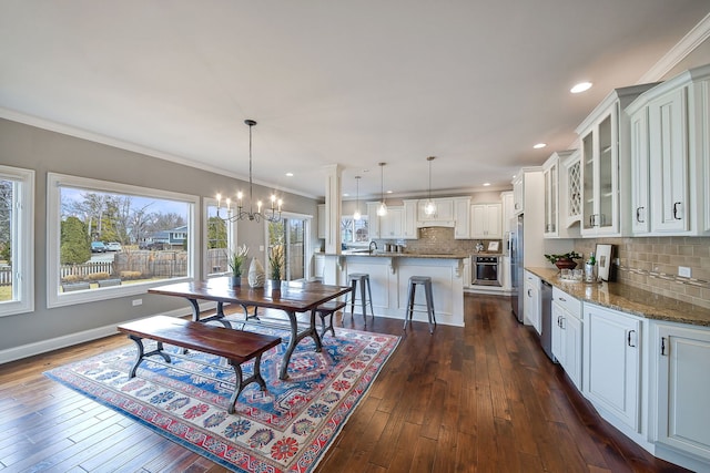 dining area featuring recessed lighting, a notable chandelier, dark wood-style flooring, baseboards, and ornamental molding