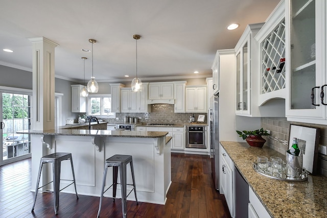 kitchen with stone counters, a breakfast bar, dark wood finished floors, appliances with stainless steel finishes, and white cabinetry