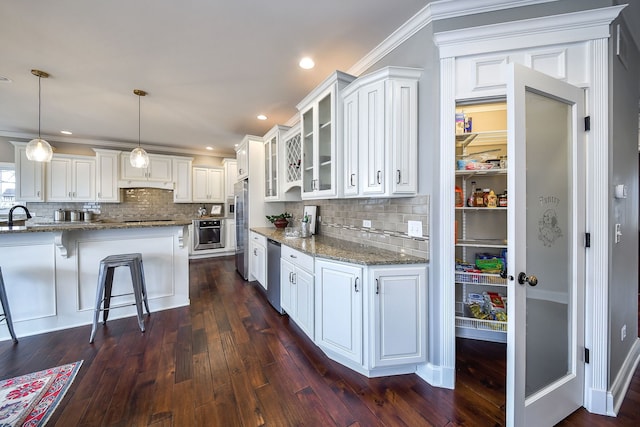 kitchen with appliances with stainless steel finishes, dark wood-style flooring, light stone counters, and white cabinets