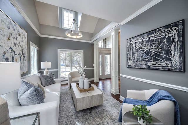 living area with baseboards, ornamental molding, wood finished floors, ornate columns, and high vaulted ceiling