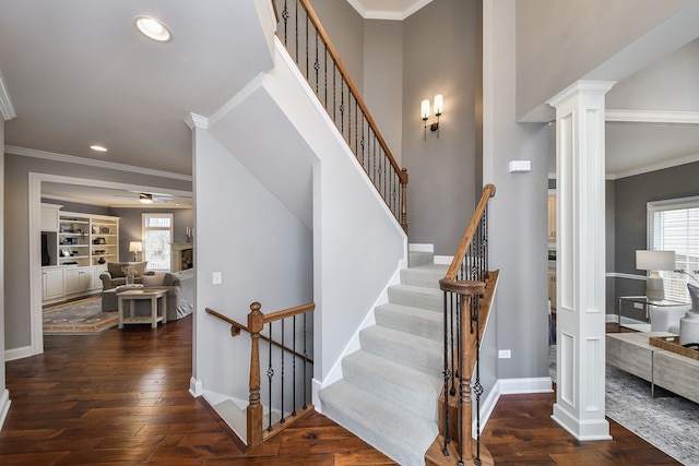 staircase with ornate columns, ornamental molding, and hardwood / wood-style floors