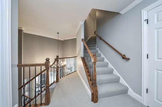 stairway featuring baseboards, ornamental molding, carpet, and an inviting chandelier