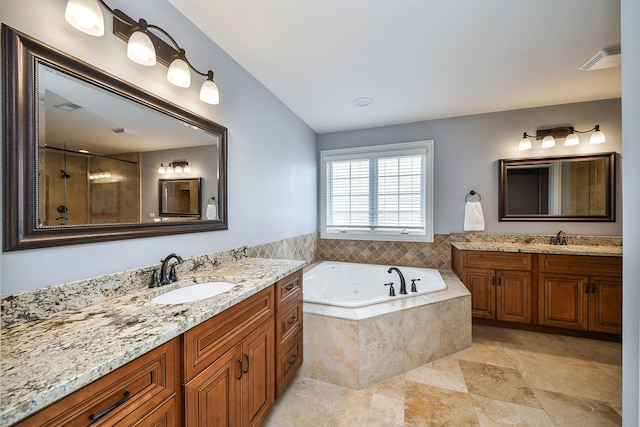 bathroom featuring a bath, visible vents, two vanities, and a sink