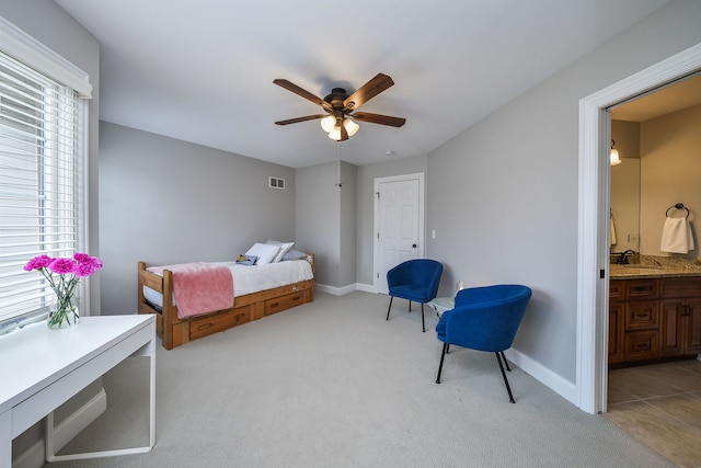 bedroom with light carpet, visible vents, baseboards, ensuite bath, and a sink