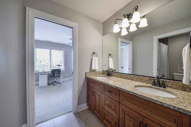 bathroom featuring double vanity, a sink, baseboards, and tile patterned floors