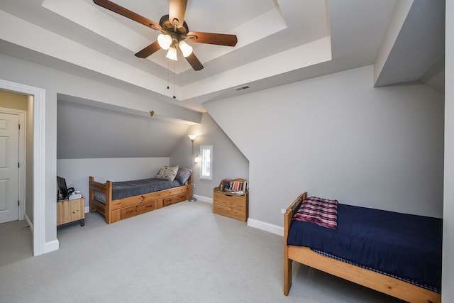 carpeted bedroom featuring a tray ceiling, visible vents, vaulted ceiling, ceiling fan, and baseboards