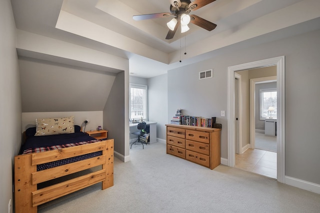 bedroom featuring light carpet, a raised ceiling, visible vents, and baseboards