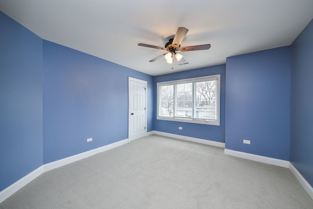 spare room with light colored carpet, ceiling fan, visible vents, and baseboards