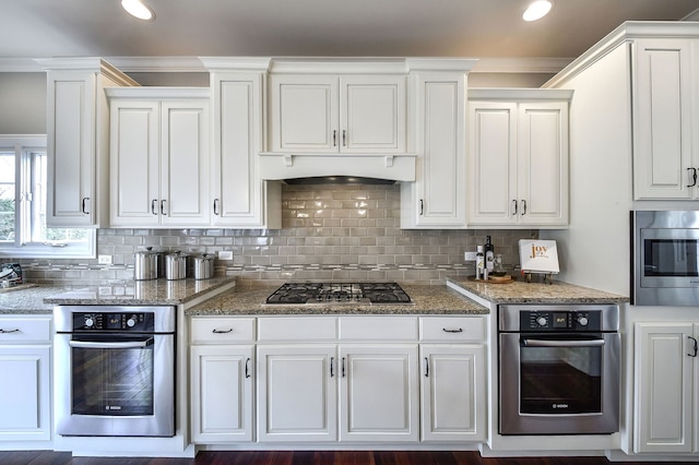 kitchen with stainless steel appliances, backsplash, and white cabinets