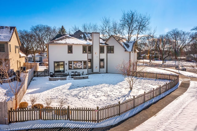 snow covered house featuring fence private yard and a chimney