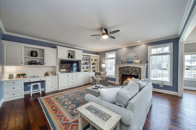 living area featuring ornamental molding, built in desk, dark wood-style flooring, and a fireplace