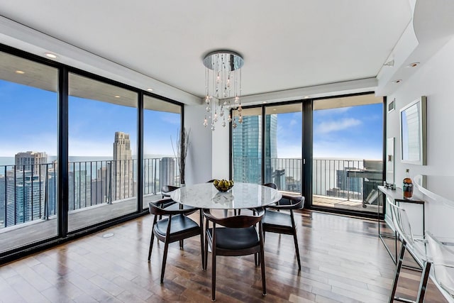 dining space with expansive windows, a water view, hardwood / wood-style floors, and a notable chandelier