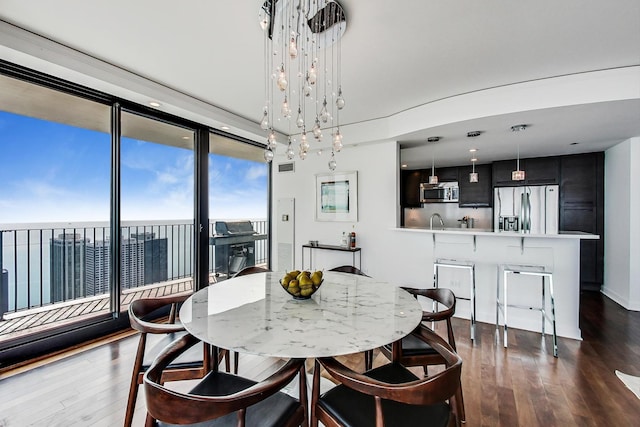 dining room featuring a notable chandelier, floor to ceiling windows, dark hardwood / wood-style floors, and a water view