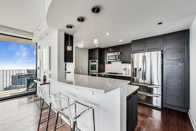 kitchen with appliances with stainless steel finishes, decorative light fixtures, a kitchen bar, dark hardwood / wood-style flooring, and floor to ceiling windows