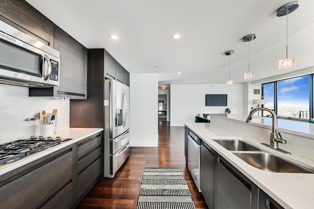 kitchen with sink, light stone counters, hanging light fixtures, dark hardwood / wood-style floors, and stainless steel appliances