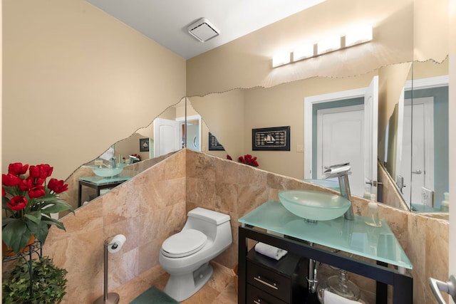 bathroom featuring vanity, tile walls, and toilet