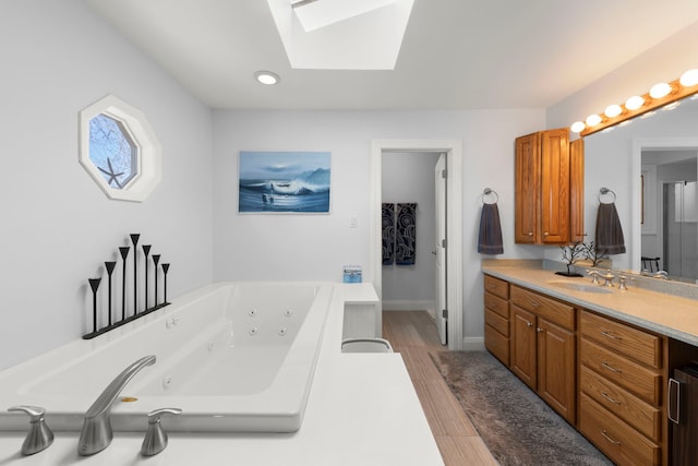 bathroom with hardwood / wood-style flooring, vanity, a bathing tub, and a skylight