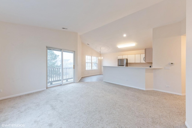 unfurnished living room with vaulted ceiling, light colored carpet, and a chandelier