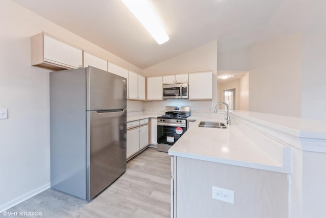 kitchen with lofted ceiling, sink, light hardwood / wood-style flooring, appliances with stainless steel finishes, and kitchen peninsula