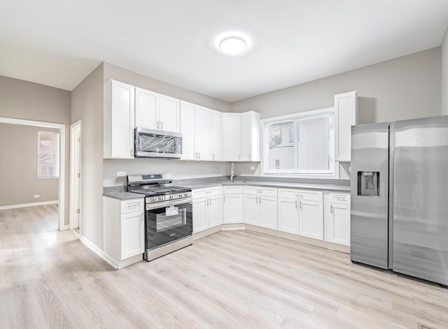 kitchen with light hardwood / wood-style floors, white cabinets, and appliances with stainless steel finishes