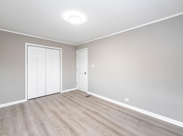 unfurnished bedroom with crown molding, a closet, and light wood-type flooring