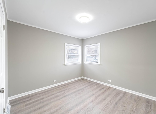 empty room with crown molding and light hardwood / wood-style floors