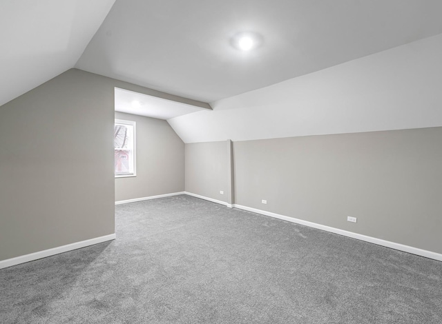 bonus room featuring vaulted ceiling and dark colored carpet