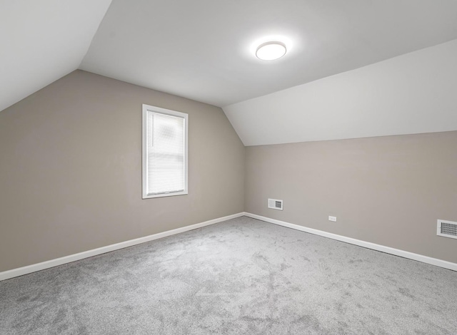 additional living space featuring vaulted ceiling and carpet flooring