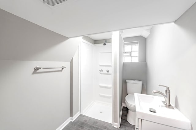 bathroom with lofted ceiling, hardwood / wood-style floors, vanity, toilet, and walk in shower