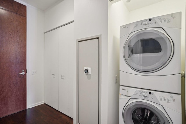 clothes washing area with dark wood-type flooring and stacked washer and clothes dryer