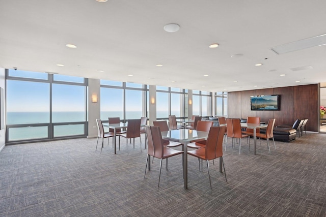 dining room featuring a water view, dark carpet, a wealth of natural light, and a wall of windows