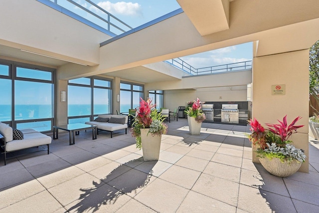 view of patio / terrace featuring a water view, grilling area, an outdoor living space, and exterior kitchen