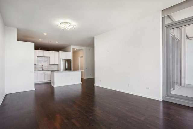 unfurnished living room featuring sink and dark hardwood / wood-style flooring