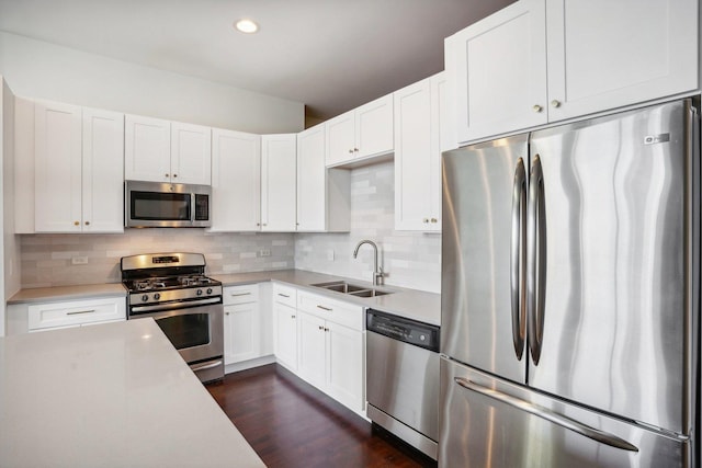 kitchen with appliances with stainless steel finishes, sink, decorative backsplash, and white cabinets