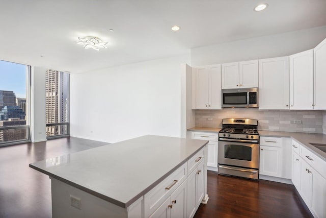 kitchen with backsplash, stainless steel appliances, a kitchen island, and white cabinets