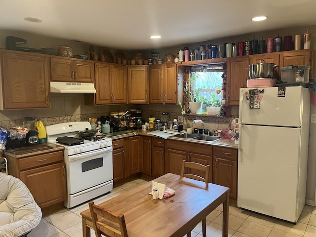 kitchen with light tile patterned flooring, sink, backsplash, and white appliances