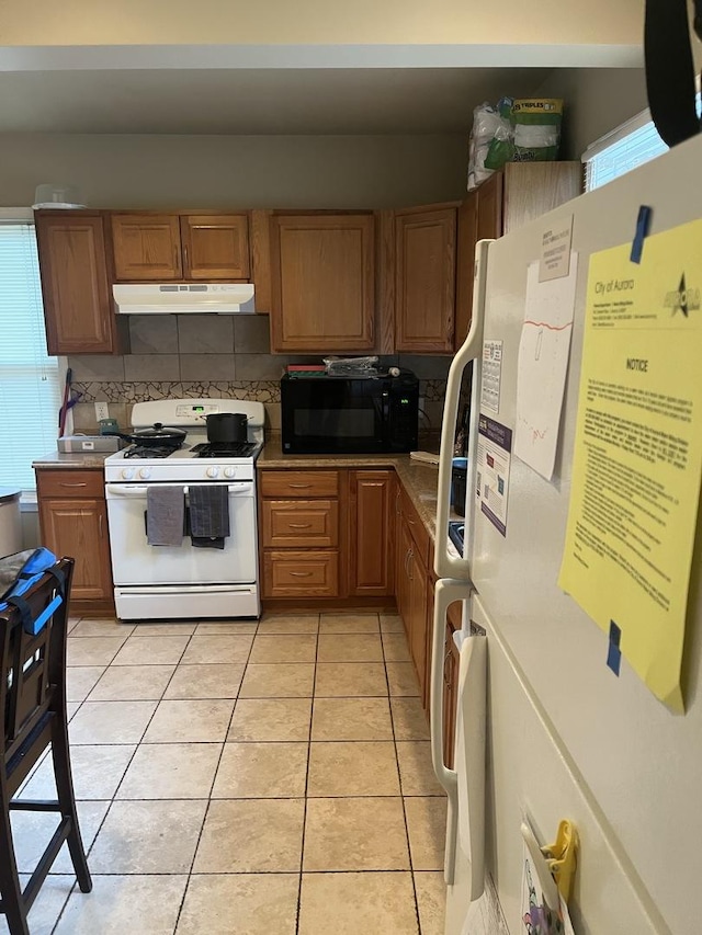 kitchen with light tile patterned flooring, white appliances, and tasteful backsplash