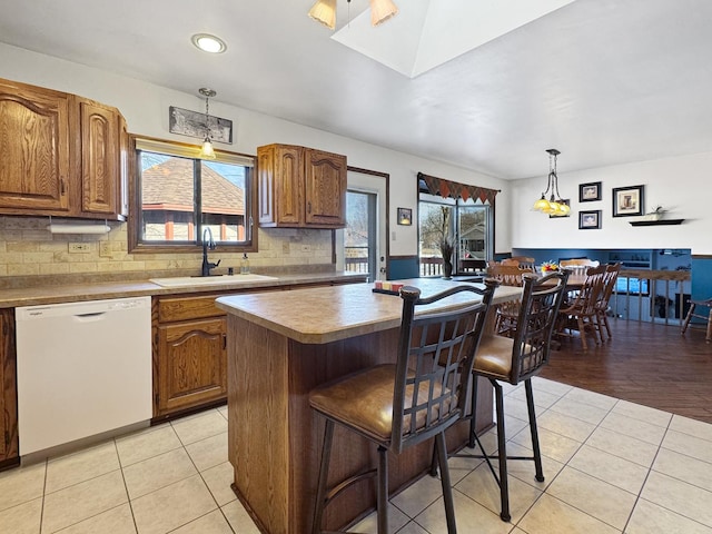 kitchen featuring sink, hanging light fixtures, a center island, light tile patterned floors, and white dishwasher