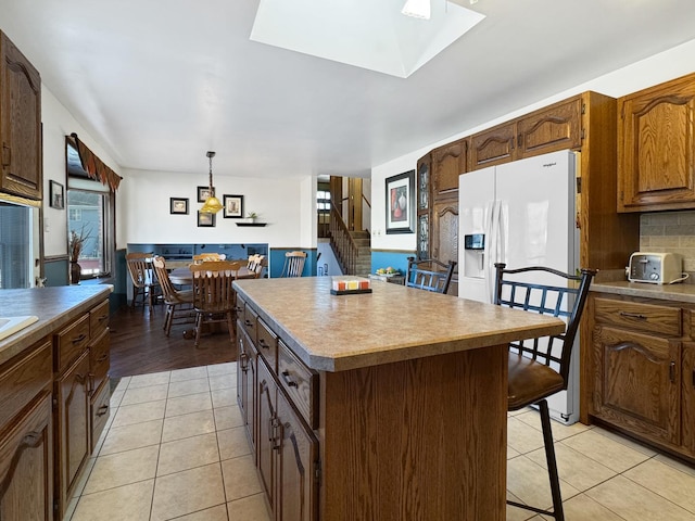 kitchen featuring light tile patterned flooring, a kitchen island, a breakfast bar, decorative light fixtures, and decorative backsplash