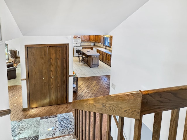 stairs with hardwood / wood-style floors and vaulted ceiling