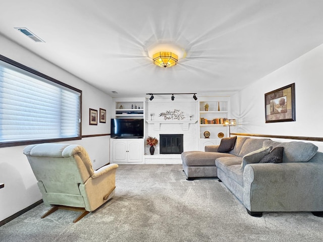 carpeted living room featuring a fireplace, built in features, and track lighting